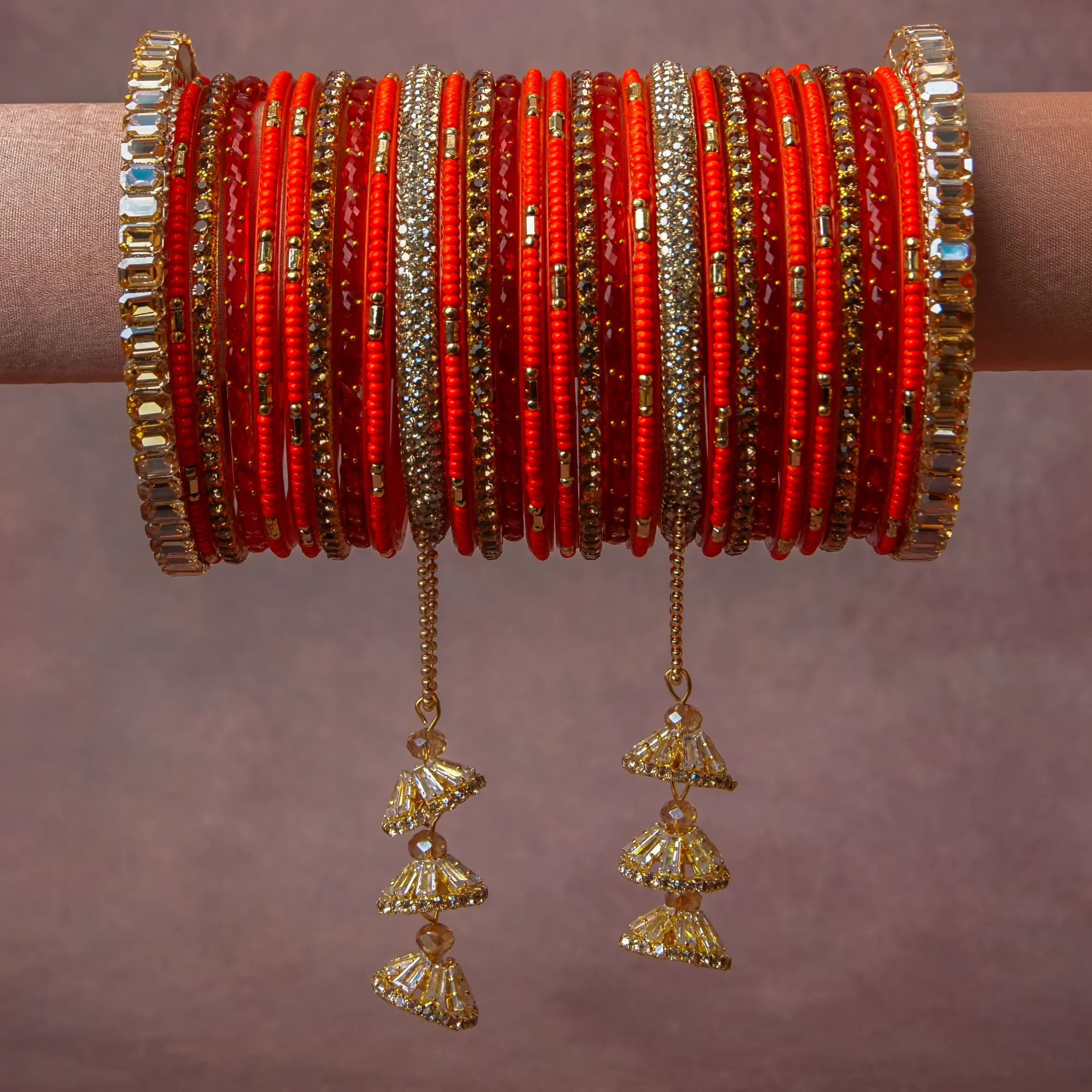 A grounding Scarlet Red forms the heart of the set, while touches of Bright Gold, Clear Faceted Crystal, Champagne Faceted Crystal add charm.

A thoughtful composition of Glass (bangles and seed beads), Gold-plated Metal (bangle frames, chains, and smaller bead elements), Faceted Glass Crystals (embellishments and dangling components), designed to feel complete without being heavy.
Each element layers seamlessly, creating a look that is refined, wearable and quietly striking.